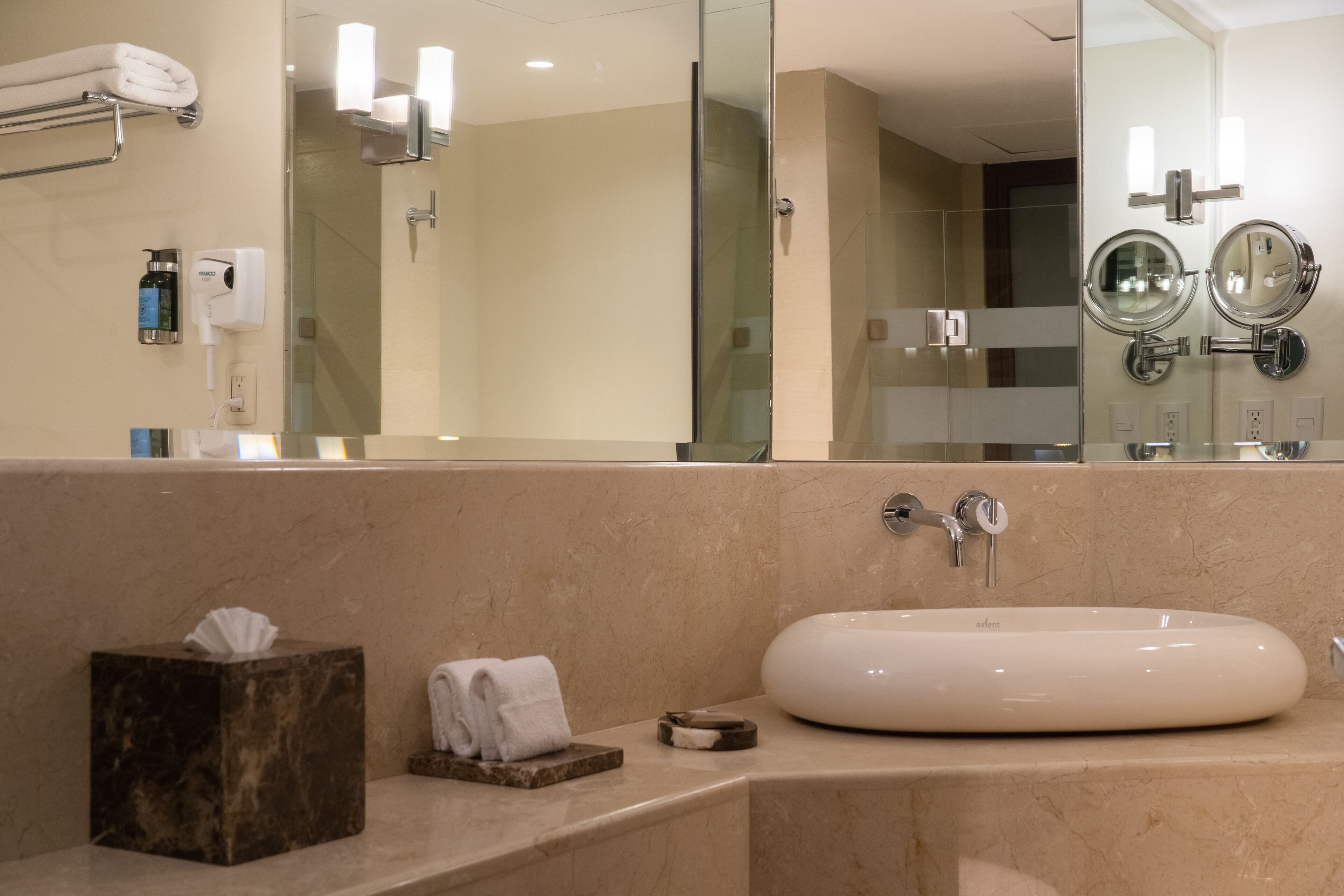 Un baño con un espejo grande, un lavabo y un perchero para toallas.