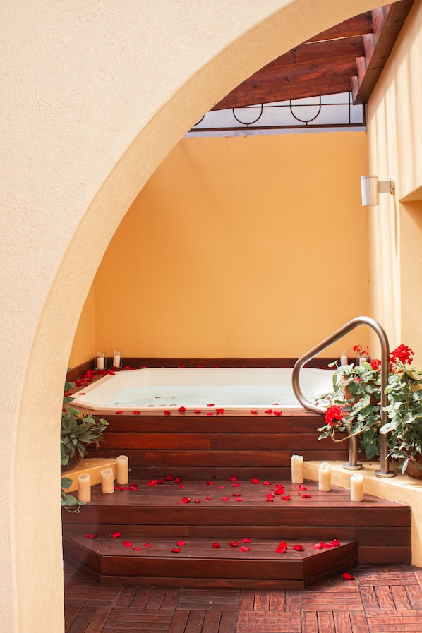 A spa area with a hot tub, wooden steps, and candles.