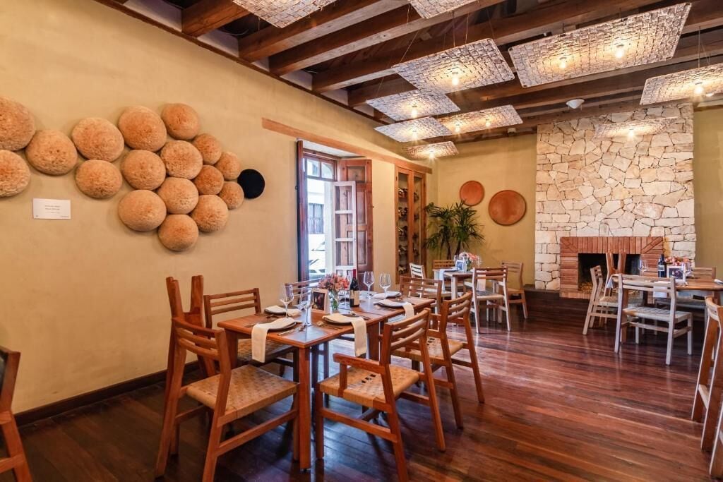 A restaurant with wooden tables and chairs, a stone wall, and a fireplace.