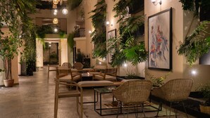 A cozy indoor seating area with wicker chairs and a small table, surrounded by potted plants and artwork on the walls. - Casa del Alma Hotel Boutique & Spa (San Cristóbal de las Casas)