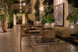 A cozy indoor seating area with wicker chairs and a small table, surrounded by potted plants and artwork on the walls. - Casa del Alma Hotel Boutique & Spa (San Cristóbal de las Casas)