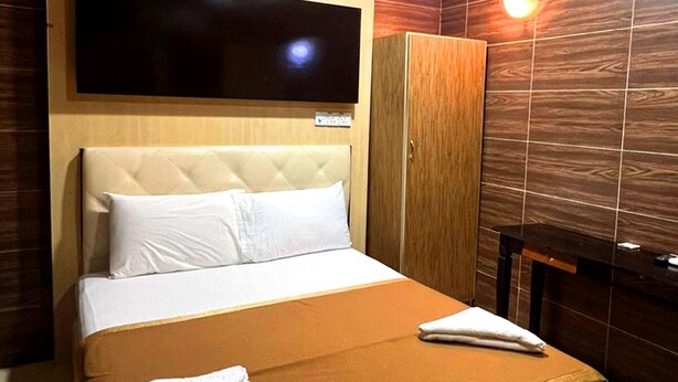 Habitación de hotel con una cama grande, un televisor en la pared, un armario y un espejo.
