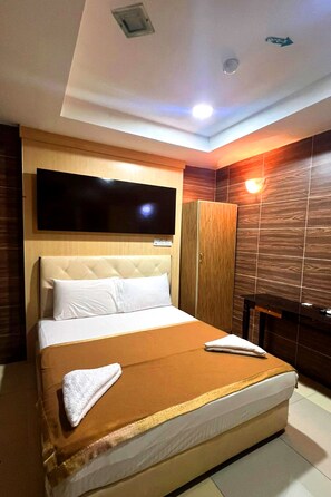 A hotel room with a large bed, a television mounted on the wall, a wardrobe, and a mirror. - Batu Caves Business Hotel (Batu Caves)