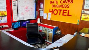 Un mostrador de recepción con un reloj, un mapa y un cartel para Batu Caves Business Hotel.