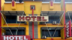Un hotel con un llamativo letrero que dice 'HOTEL' en el centro, varias unidades de aire acondicionado y una fachada roja y amarilla.