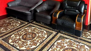 Una habitación con paredes rojas, dos sillones de cuero negro, una alfombra estampada y una pared de acento amarilla.