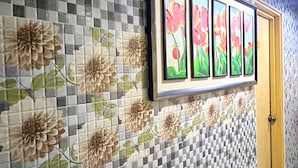 Un pasillo con pared de baldosas a cuadros y motivos florales, una obra de arte enmarcada con flores y una puerta de madera.