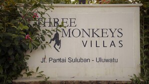 Schild für 'Three Monkeys Villas' mit einer Affen-Silhouette und Angaben zur Lage.