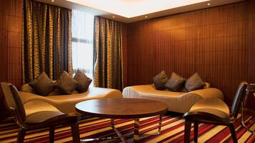 A hotel room with a sofa set, a round table, and a striped carpet.