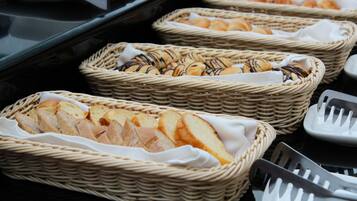Cestas de mimbre llenas de pan y bollería sobre una mesa de buffet.