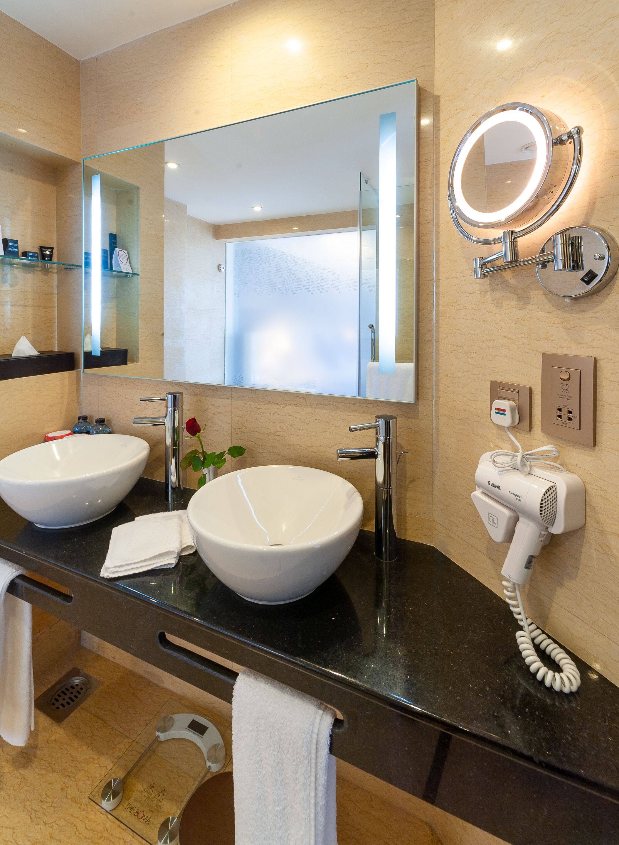 A modern bathroom with two sinks, a large mirror, a hairdryer, and a towel rack.