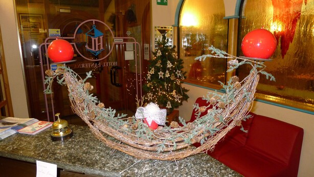A Christmas decoration with a woven structure, two red balloons, and a Christmas tree. - La Lanterna (Chiesa in Valmalenco)