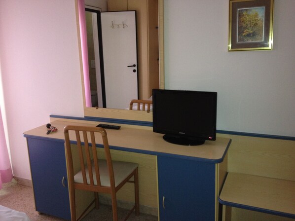 A room with a desk, a chair, a television, a wardrobe, and a door. - Trocadero (Riccione)