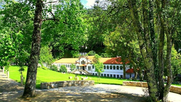 A historic building with a central courtyard, surrounded by lush greenery and trees.