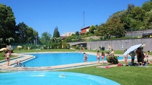 A swimming pool area with multiple pools, umbrellas, and people.