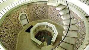 A spiral staircase with a patterned floor, leading to an upper level.