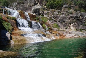 A multi-tiered waterfall cascading over rocky terrain into a clear pool.