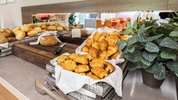 Un bufé con una variedad de productos de panadería, incluyendo pan y pasteles, dispuestas sobre tablas y bandejas de madera.