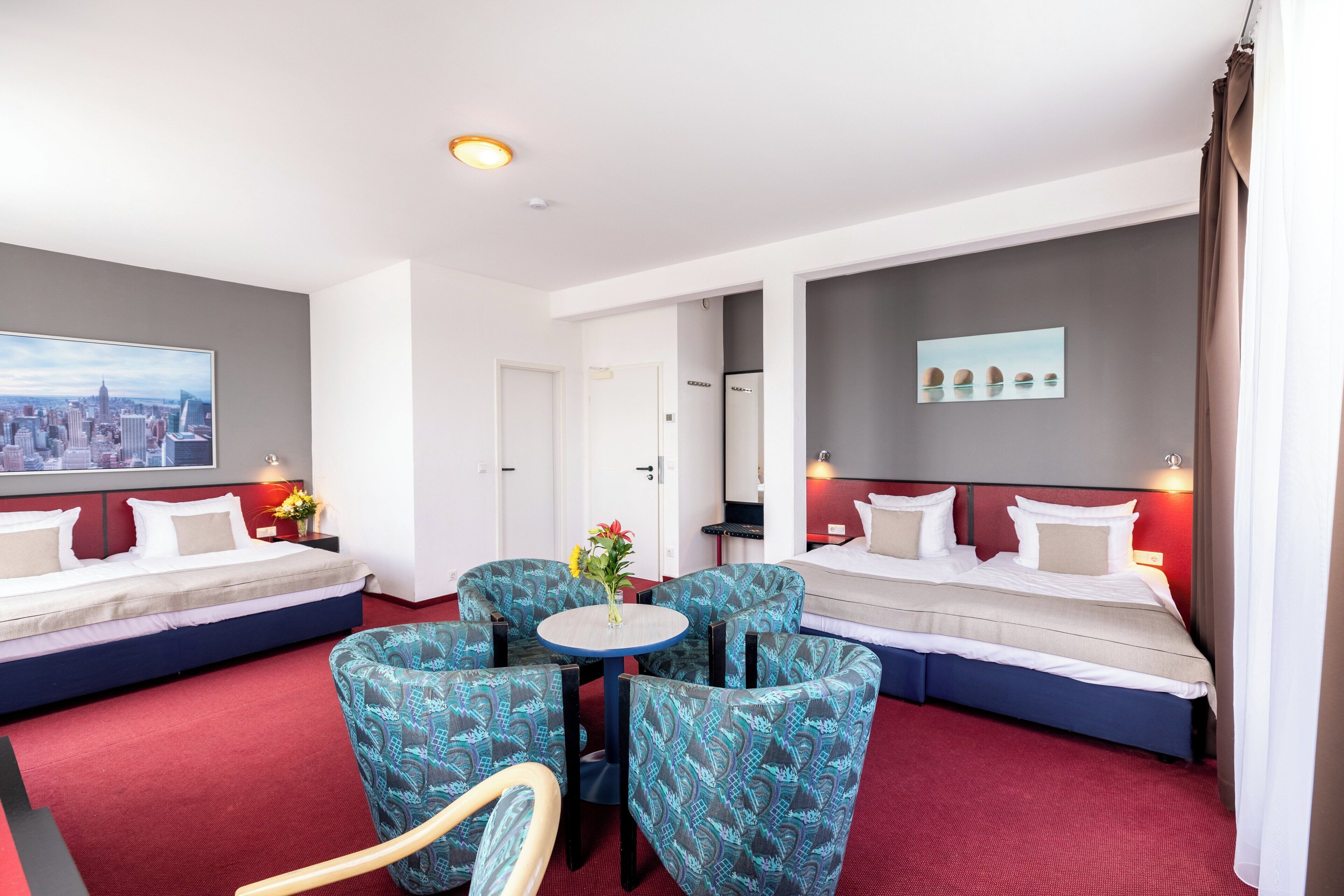 Habitación de hotel con dos camas, vistas a la ciudad, una mesa de comedor y sillas estampadas.