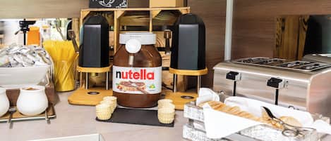 Uma bancada de cozinha com um pote de Nutella, máquina de café e diversos utensílios de cozinha.