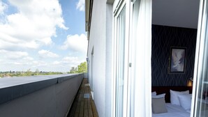 A hotel room with a balcony, a bed with white linens, a dark patterned wall, and a framed picture on the wall. - Hotel Aviva (Leipzig)