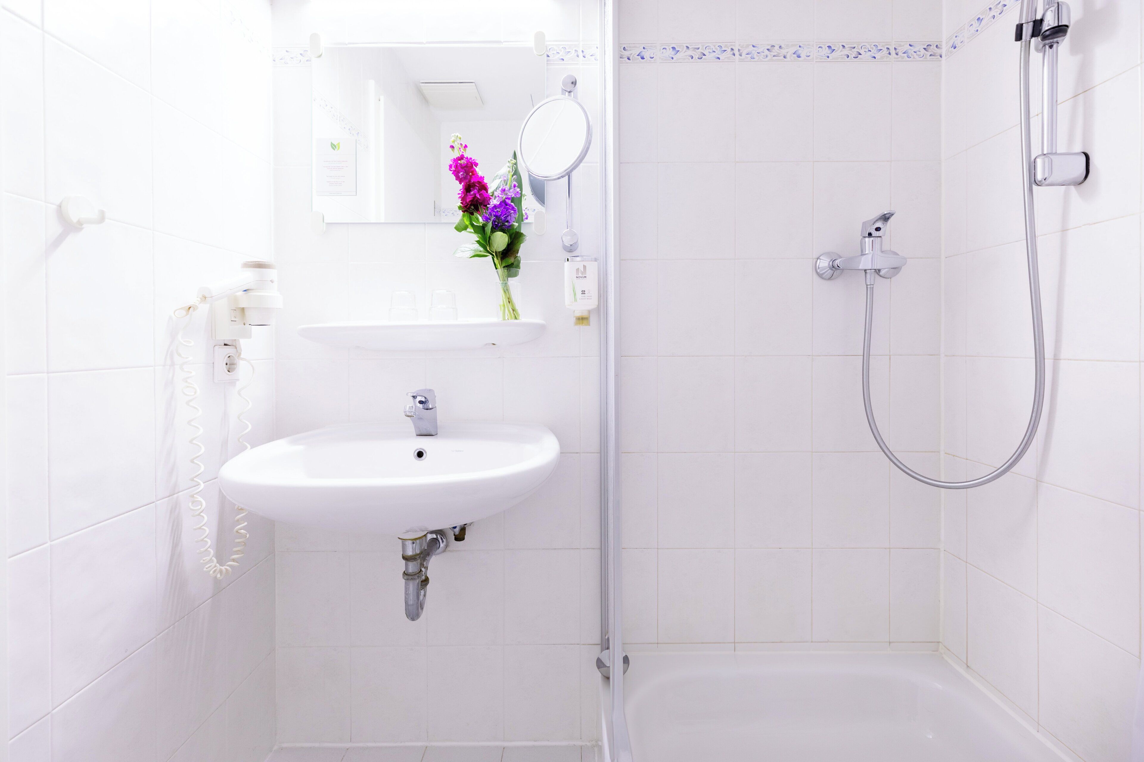 Ein Badezimmer mit Waschbecken, Spiegel und Dusche.