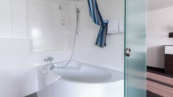 A modern bathroom with a white bathtub, a glass shower enclosure, and a visible towel rack.