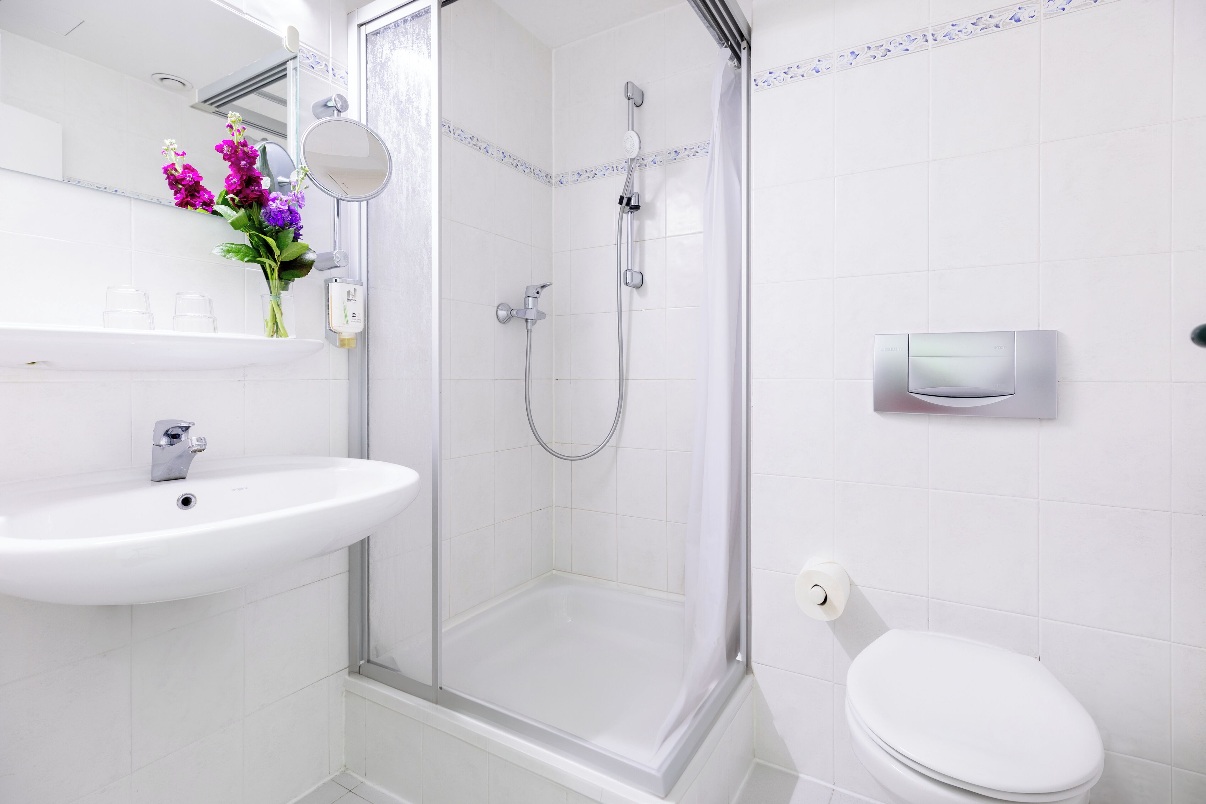 Une salle de bain moderne avec une douche à parois de verre, un lavabo blanc et des toilettes.