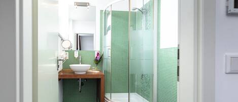 Un bagno moderno con cabina doccia a forma curva, un mobile bagno in legno e un lavandino bianco.