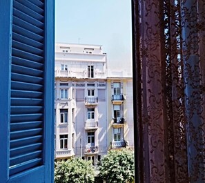 A multi-story building with balconies and a window with blue shutters.