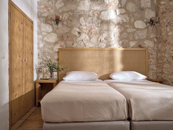 A double bed with a woven headboard in a room with stone walls and wooden furniture. - Orfos Villas (Zakynthos)