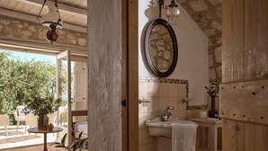 A bathroom with a stone wall, a wooden door, a sink with a towel, and a mirror.