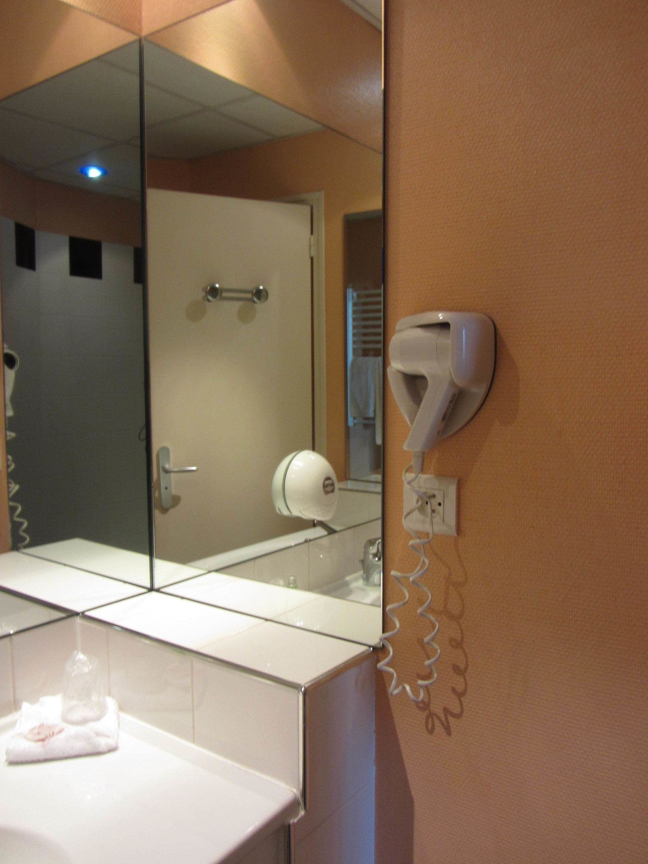 A bathroom with a mirror, a towel rack, and a hairdryer.