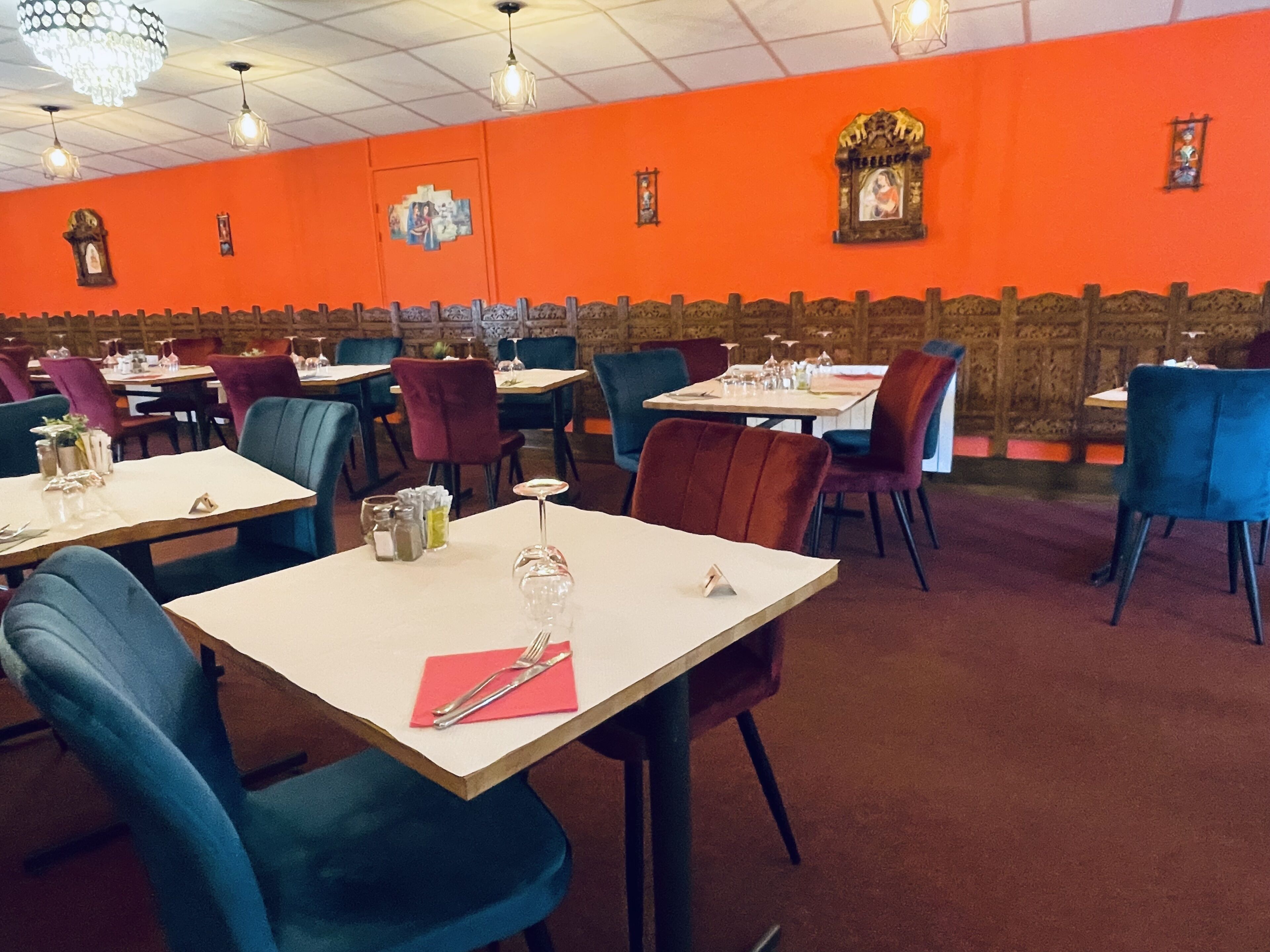 A restaurant with tables and chairs, orange walls, and a wooden accent wall.