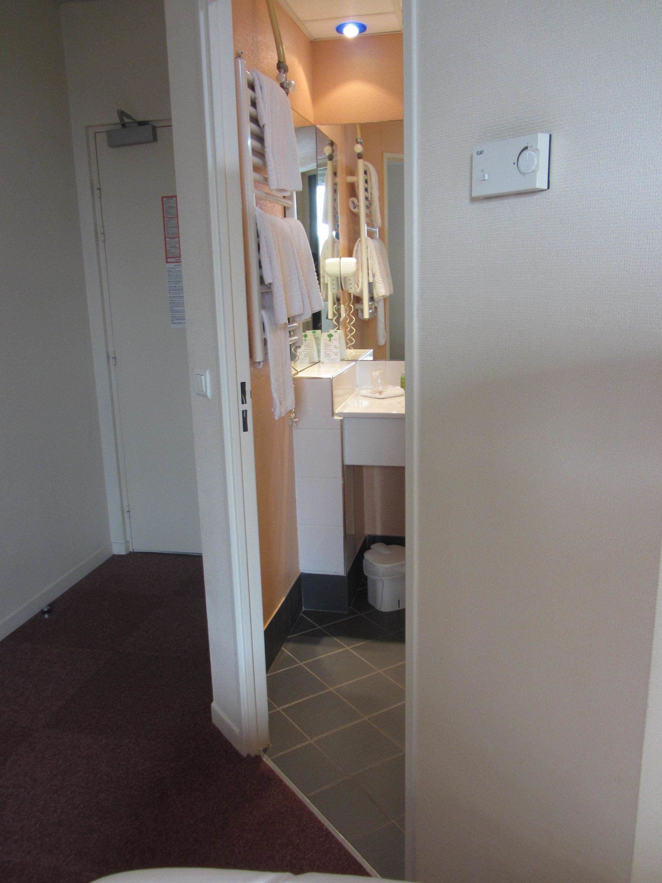 A hotel bathroom with a sink, mirror, and towel rack.