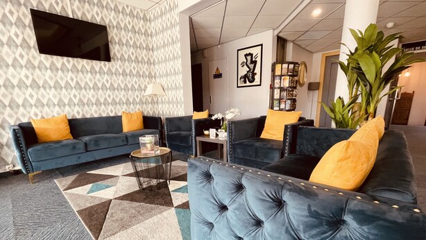 Un hall d’entrée moderne avec un canapé bleu, un tapis à motifs et une grande plante.