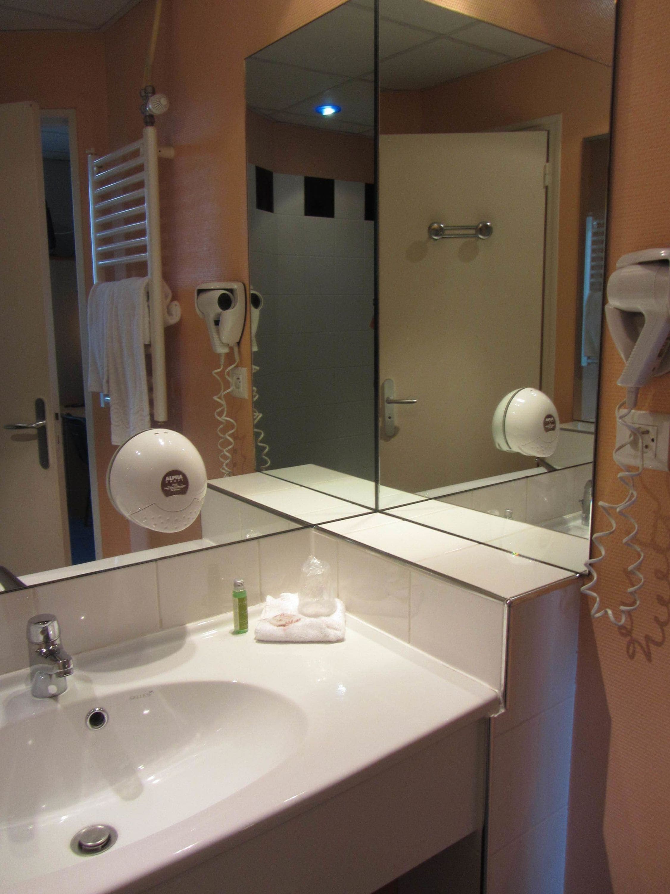 Un baño con lavabo, espejo, toallero y secador de pelo.