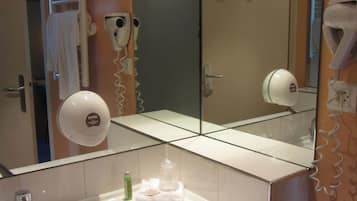 Un baño con lavabo, espejo, toallero y secador de pelo.