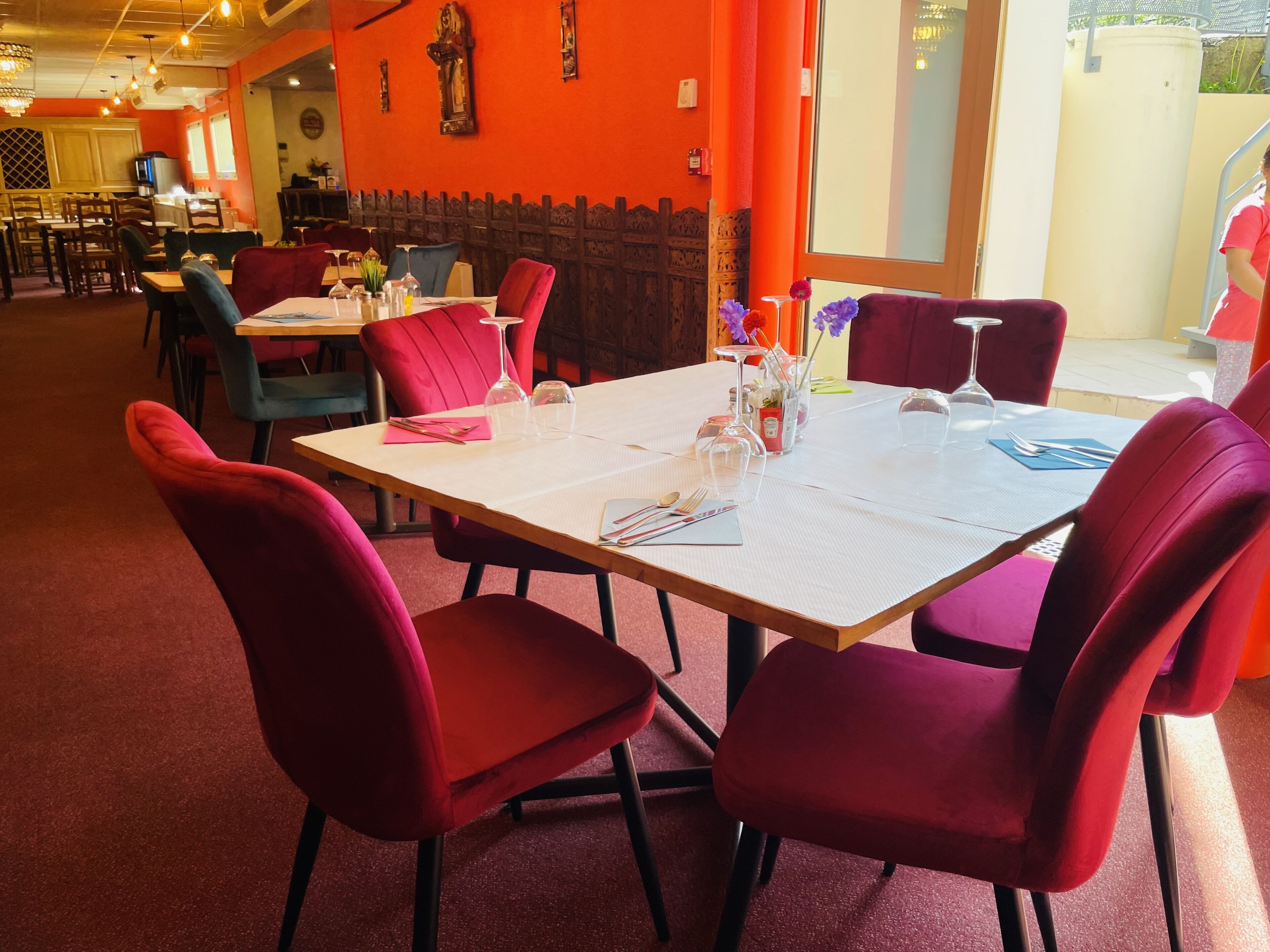 A restaurant with red upholstered chairs, a white table, and a wooden partition.