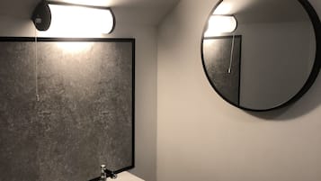 A bathroom with a white sink, a rectangular mirror with a black frame, and a round mirror.