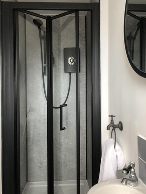 A modern bathroom with a glass-enclosed shower, a white sink, and a mirror above it. - The Metropolitan (Whitley Bay)