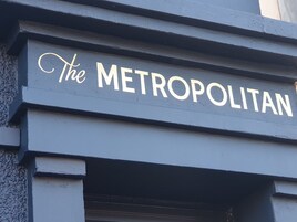 Un letrero con el texto "The METROPOLITAN" en la fachada de un edificio.
