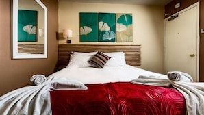 Una habitación de hotel con una cama, un espejo y obras de arte en la pared.