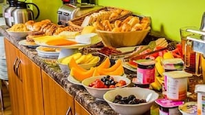 Un bufé con diferentes opciones de comida, como frutas, quesos y productos de repostería.