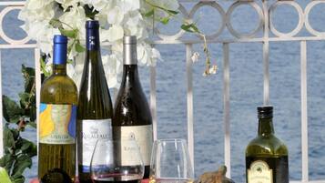 A table with seafood, vegetables, and wine bottles, with a view of the sea and a castle in the background.