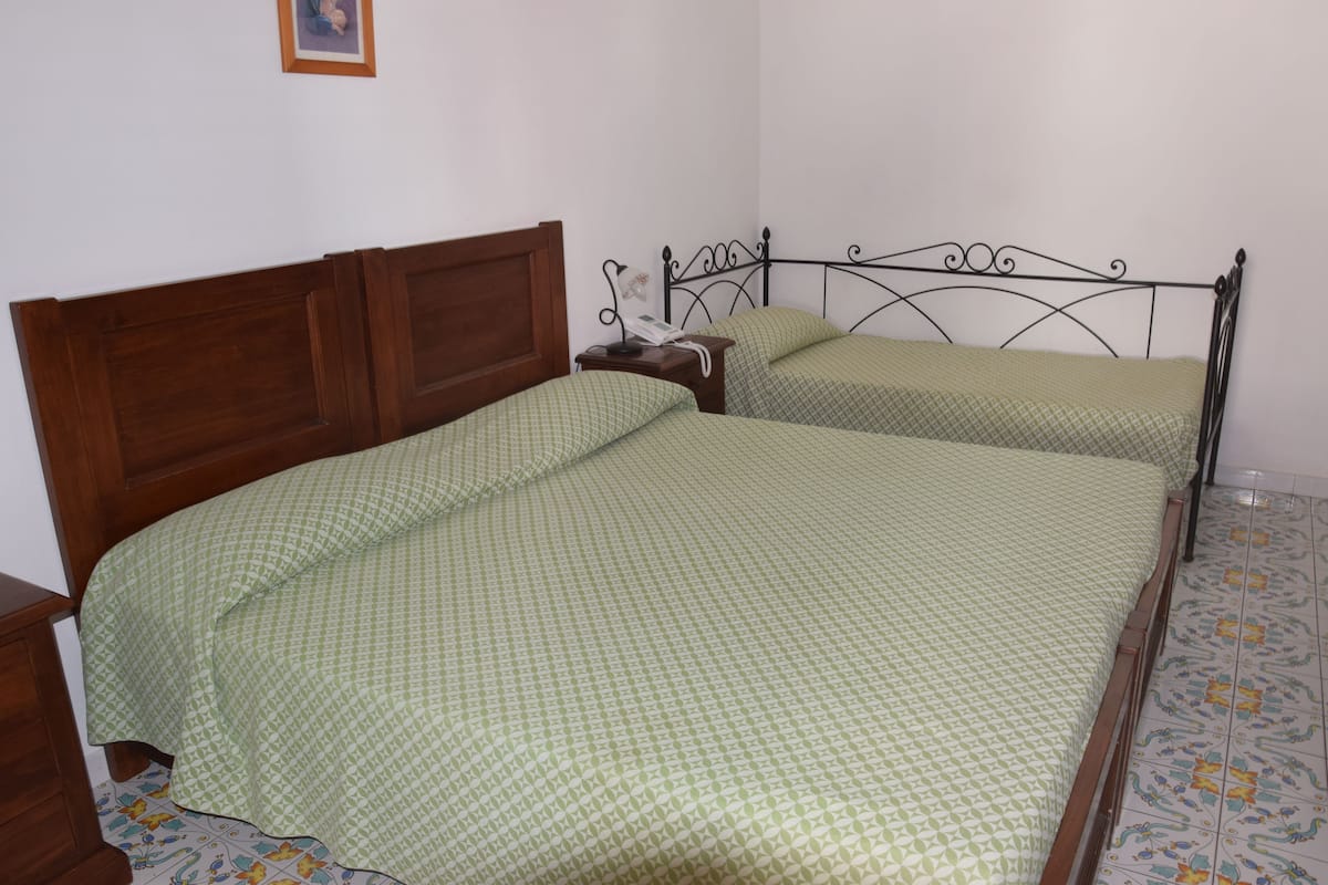 Une chambre avec deux lits simples, des têtes de lit en bois et une table de chevet avec une lampe.
