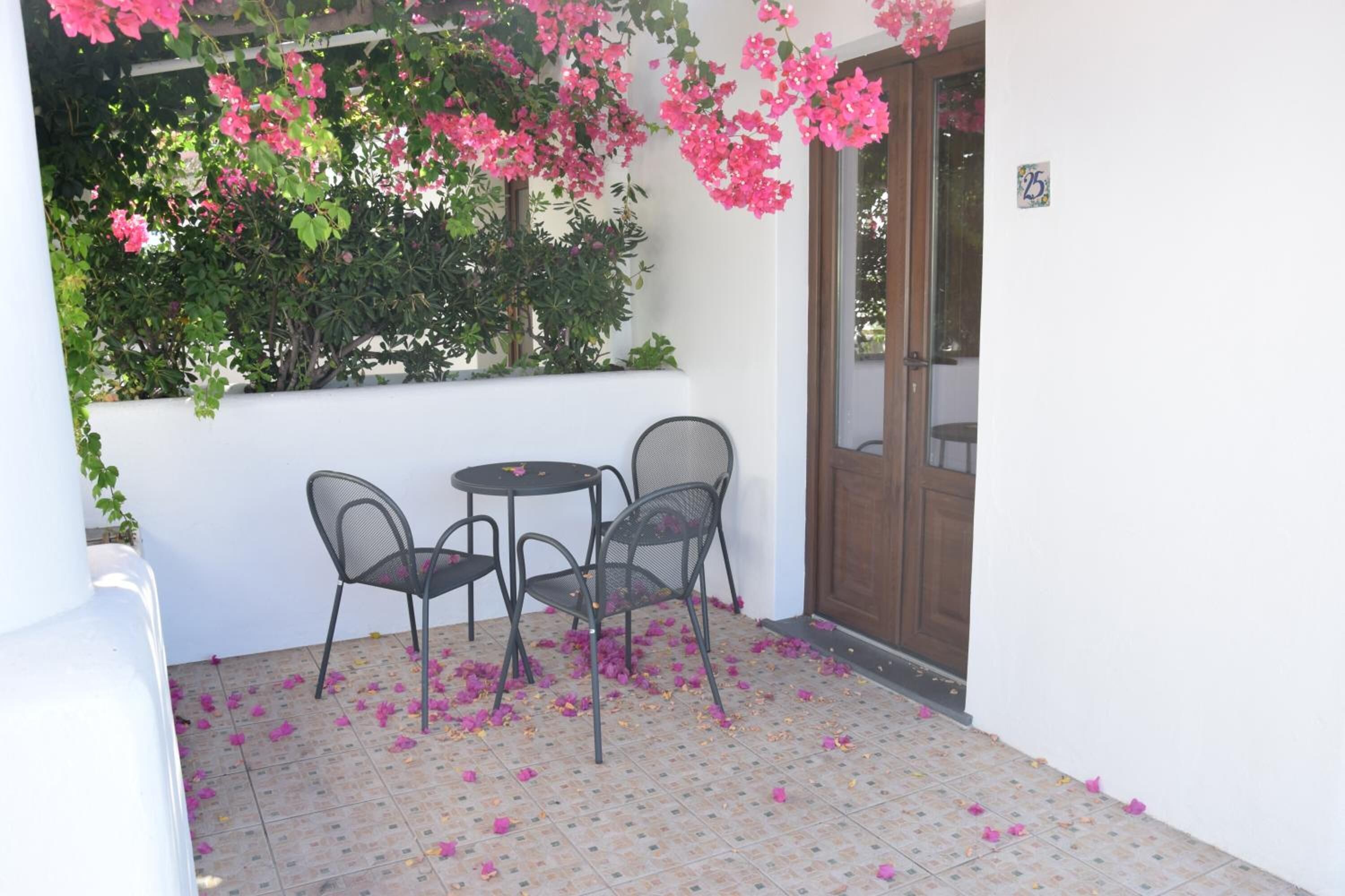 A small patio with a table and chairs, surrounded by a white wall and a wooden door.
