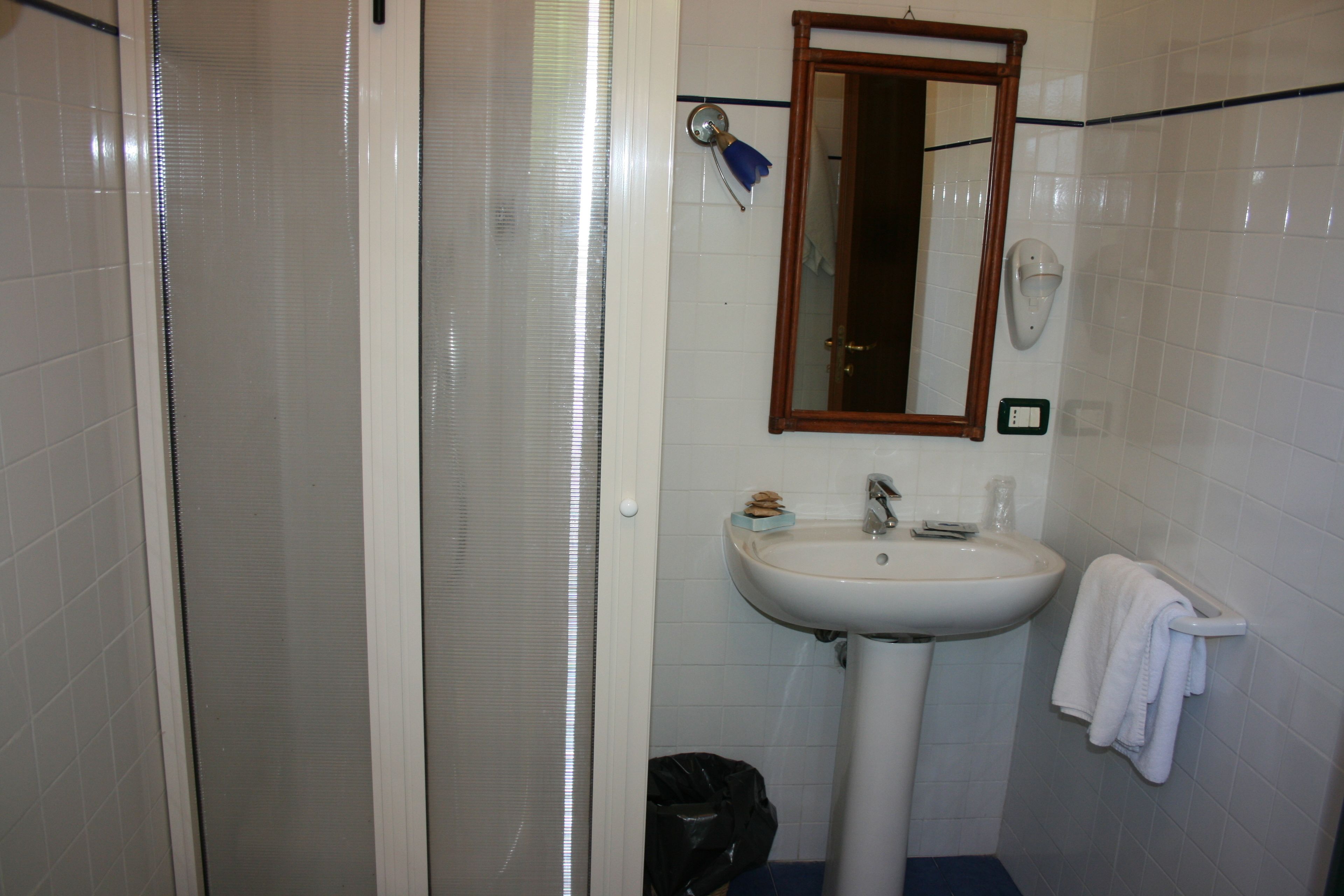A bathroom with a shower, sink, and mirror.