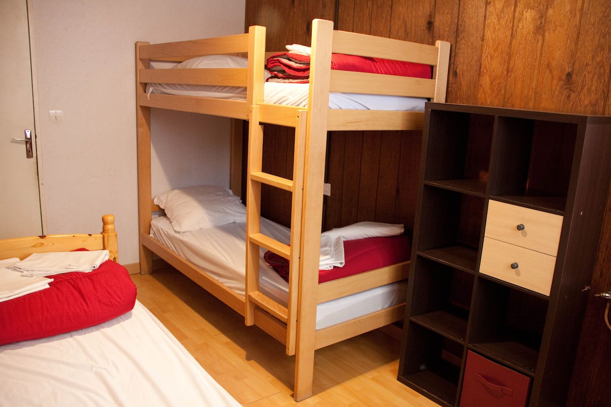 A bunk bed room with a wooden wardrobe and a door.