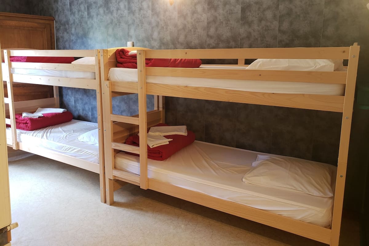 A bunk bed room with a grey textured wall and a wooden headboard.